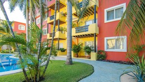 Un hôtel à plusieurs étages doté de balcons, d’une piscine et d’un aménagement paysager de style tropical.