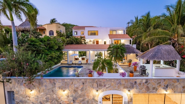Un complejo turístico con piscina, mobiliario exterior y sombrillas de paja.