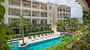 Un hôtel à plusieurs étages doté d’une piscine, de palmiers et d’une galerie couverte.
