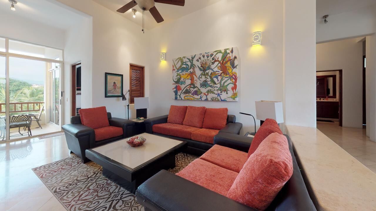 A spacious living room with a sectional sofa, a coffee table, and a large abstract painting on the wall.