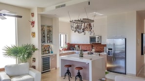 A modern kitchen with a central island, stainless steel appliances, and a hanging pot rack.