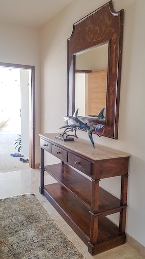A wooden vanity with a large mirror, a small desk, and a decorative shark model.