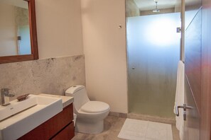 A bathroom with a white toilet, a sink, and a glass shower enclosure.