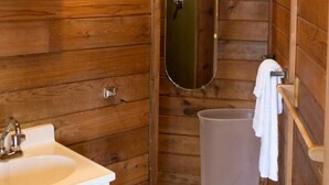 A wooden cabin bathroom with a sink, mirror, and towel rack.