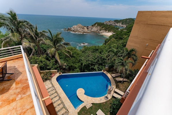 Piscina no terraço com vista para o oceano e uma costa rochosa.