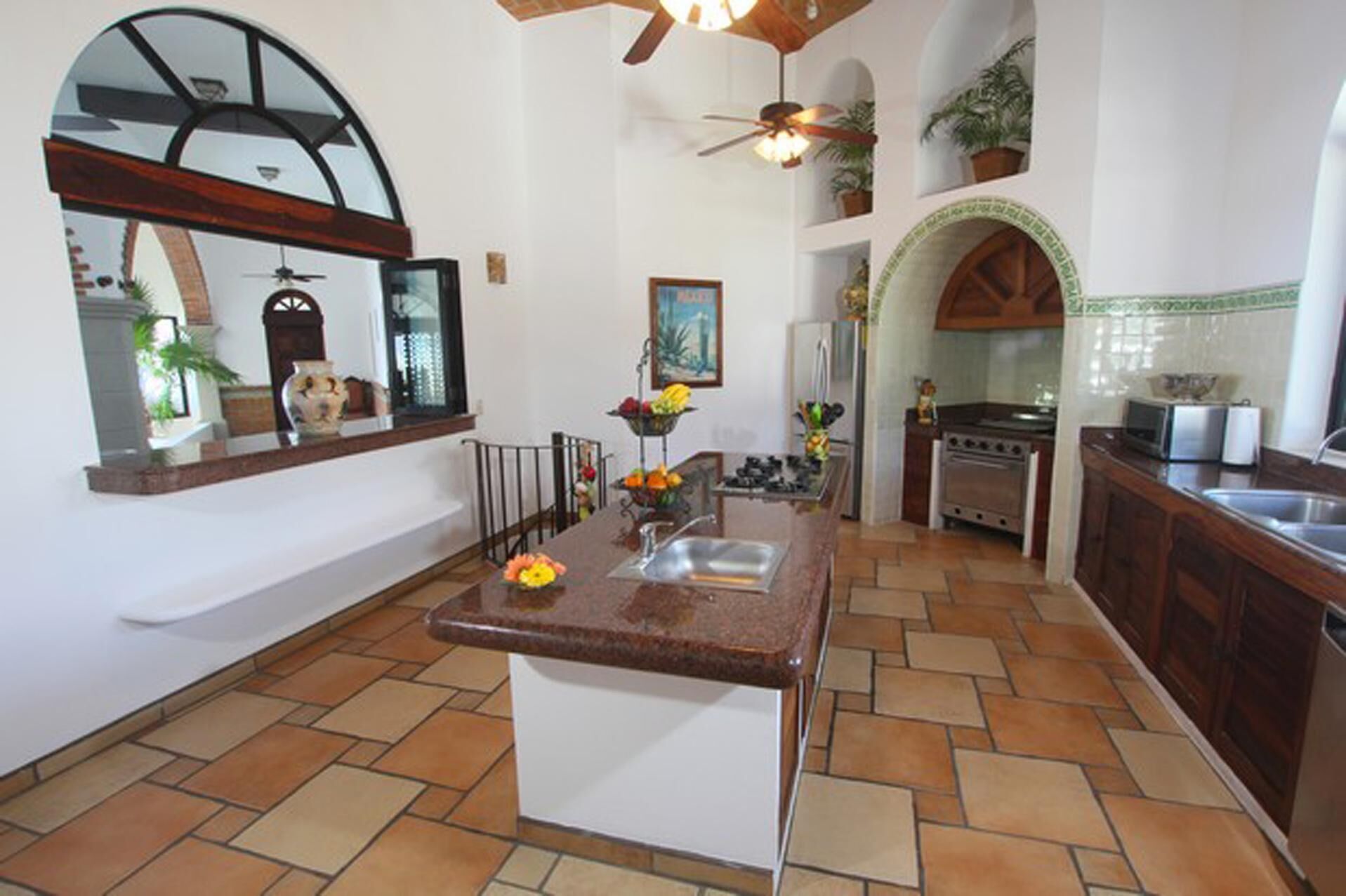 A kitchen with a central island, a ceiling fan, and a tiled floor.