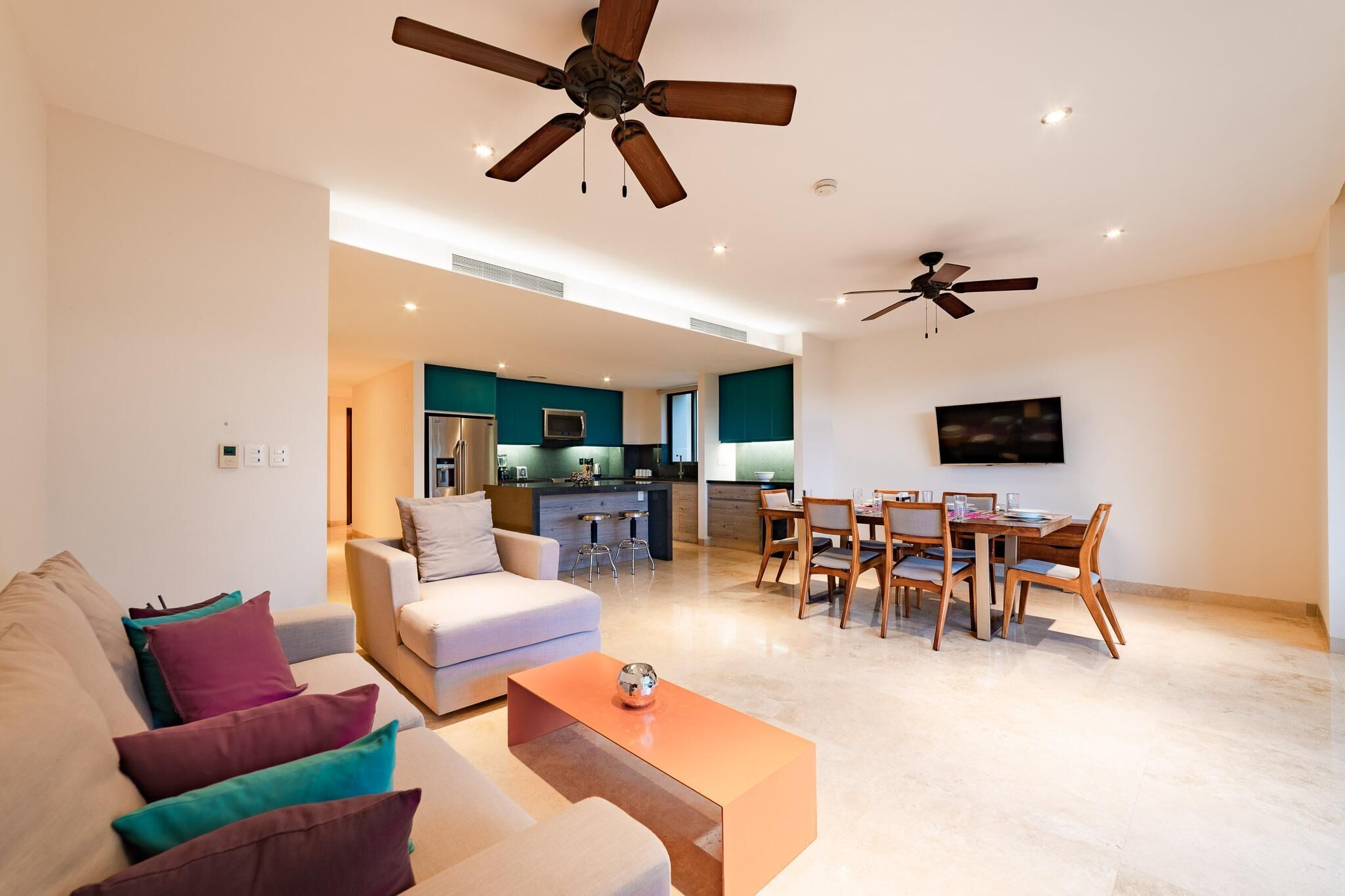 A modern living room with a sofa, coffee table, and a dining area with chairs and a table.