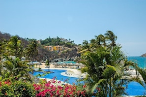A resort with a large pool, beach area, and tropical vegetation. - Residencias Lu Iba Condo 1 (Santa María Huatulco)