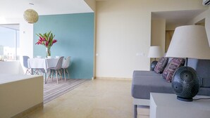 Una sala moderna con un sofá gris, una mesa de comedor con sillas y un jarrón de flores.