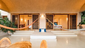 A spacious room with a large bed, wooden furniture, and a hammock. - Villa Alheli (Santa María Huatulco)