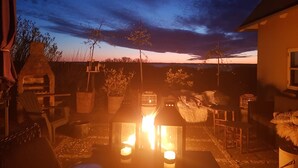 Eine Terrasse mit Steinofen, Sitzgelegenheiten und einem Feuerkorb.