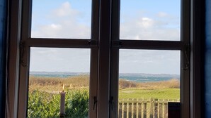 Ein Fenster mit Blick auf eine ländliche Landschaft, Felder und einen Zaun.