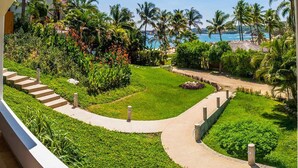A lush garden with a pathway leading to a beach view. - Villa Lu Iba (Santa María Huatulco)
