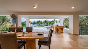 A spacious dining area with a view of a beach and palm trees. - Villa Lu Iba (Santa María Huatulco)
