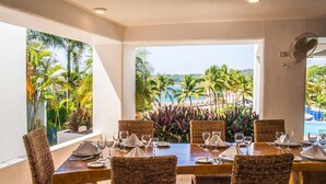 A dining area with a view of a beach and palm trees. - Villa Lu Iba (Santa María Huatulco)