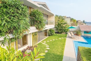 A modern house with a large glass window, a swimming pool, and a well-maintained garden.