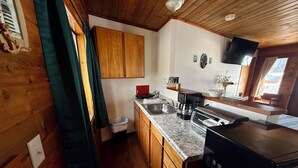 A kitchen with wooden cabinets, a granite countertop, a coffee maker, a toaster, and a black refrigerator.