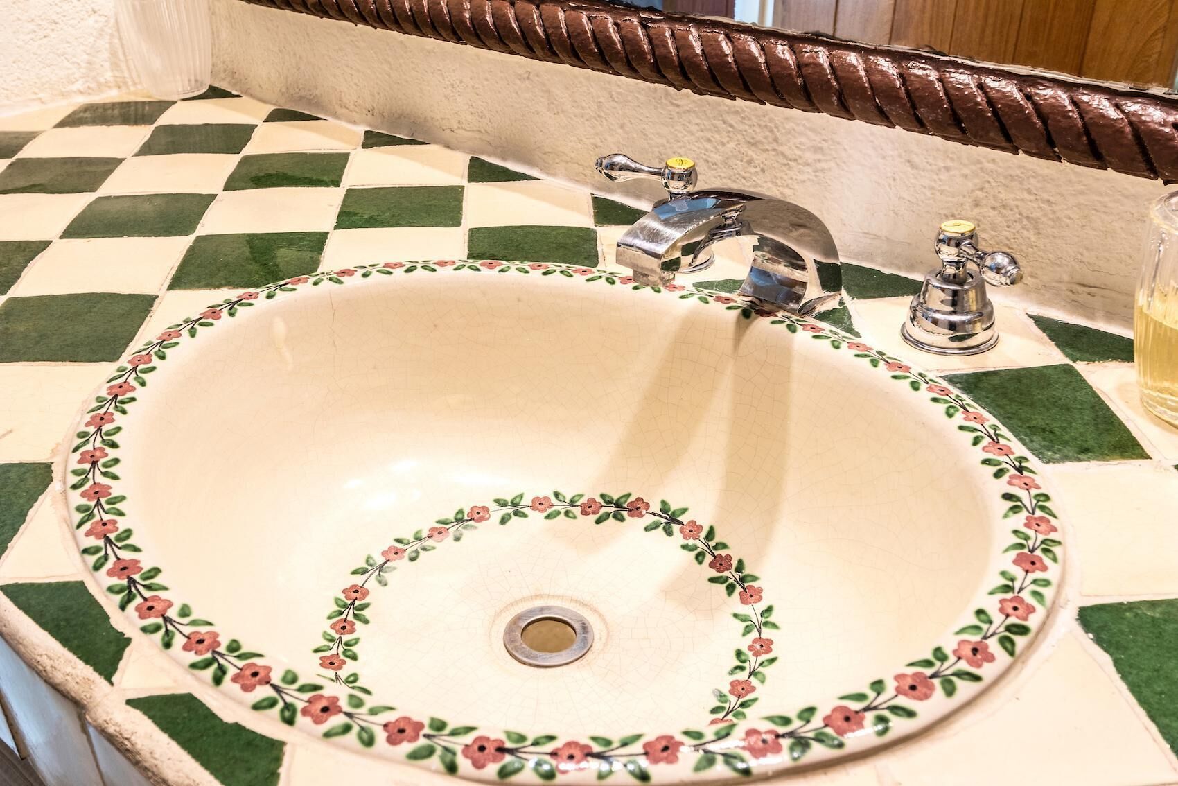 Un lavabo de bany amb una motllura floral i un terra amb un dibuix de ratlles.