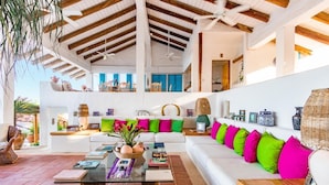A spacious living area with a white sofa, colorful cushions, a glass coffee table, and a ceiling fan. - Villa Roxana (Santa María Huatulco)