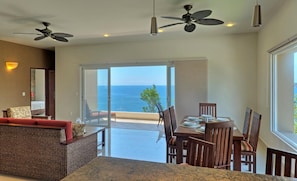 A spacious room with a balcony overlooking the sea, furnished with a dining table, chairs, and a sofa. - Punta Arrocito D202 (Santa María Huatulco)