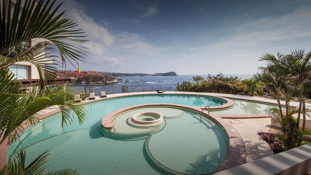 A swimming pool with a circular design, surrounded by palm trees and overlooking a coastal view. - Punta Arrocito D202 (Santa María Huatulco)
