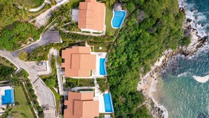 A coastal property with multiple buildings, a swimming pool, and a beach.