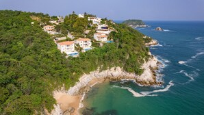 A coastal residential area with houses on a hillside overlooking the sea.