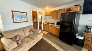A compact living space with a kitchenette, a sofa, and a framed picture on the wall. - Scenic Bay Motel room 2 (Bayview)