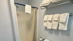 A bathroom with a shower, toilet, and towel rack. - Scenic Bay Motel room 2 (Bayview)