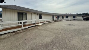 A row of single-story buildings with white exteriors and wooden railings. - Scenic Bay Motel room 2 (Bayview)
