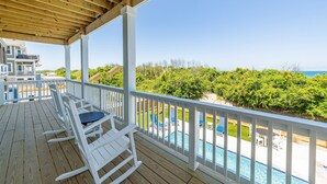 A wooden deck with white railings, a pool, and a view of the ocean. - Aftermath - Corolla, Ocean Sands, Oceanfront Luxury, Pool, Hot Tub, Elevator, Rec Room (Corolla)