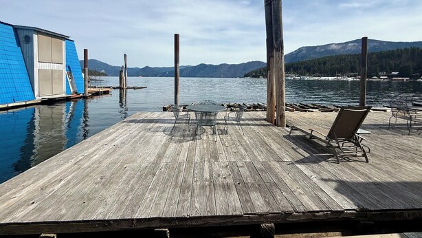 A wooden dock extending into calm water, with a building with blue siding and a door on the left. - Captain's Quarters (Bayview)
