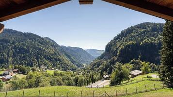 A wooden structure with a view of a valley, houses, and forested hills.