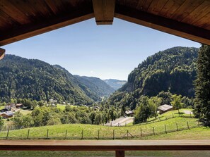 Eine Holzhütte mit Blick auf ein Tal, Häuser und bewaldete Hügel.