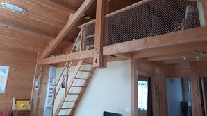 A wooden interior with a loft area, a staircase, and a mesh enclosure. - Chalet 1 to 5 persons garden and terrace with pergola in residential park (Soulac-sur-Mer)