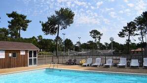 A swimming pool with lounge chairs and a wooden building with a sign. - Chalet 1 to 5 persons garden and terrace with pergola in residential park (Soulac-sur-Mer)