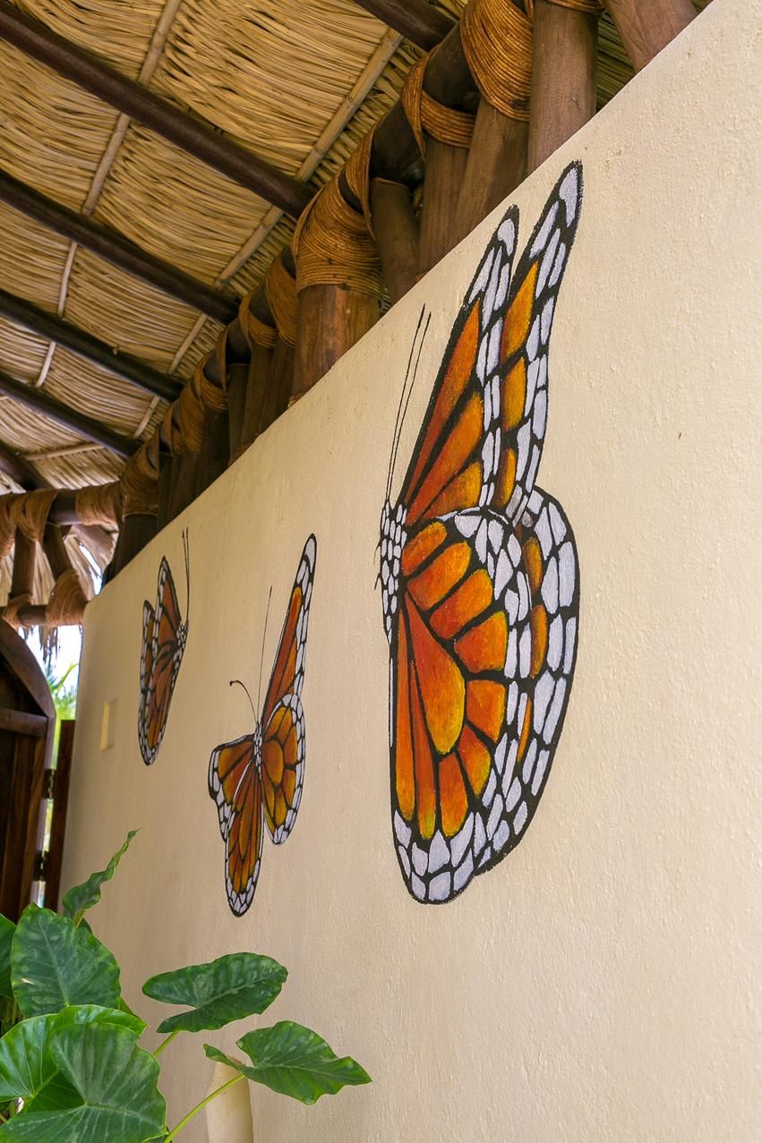 Un mur orné de trois papillons peints.