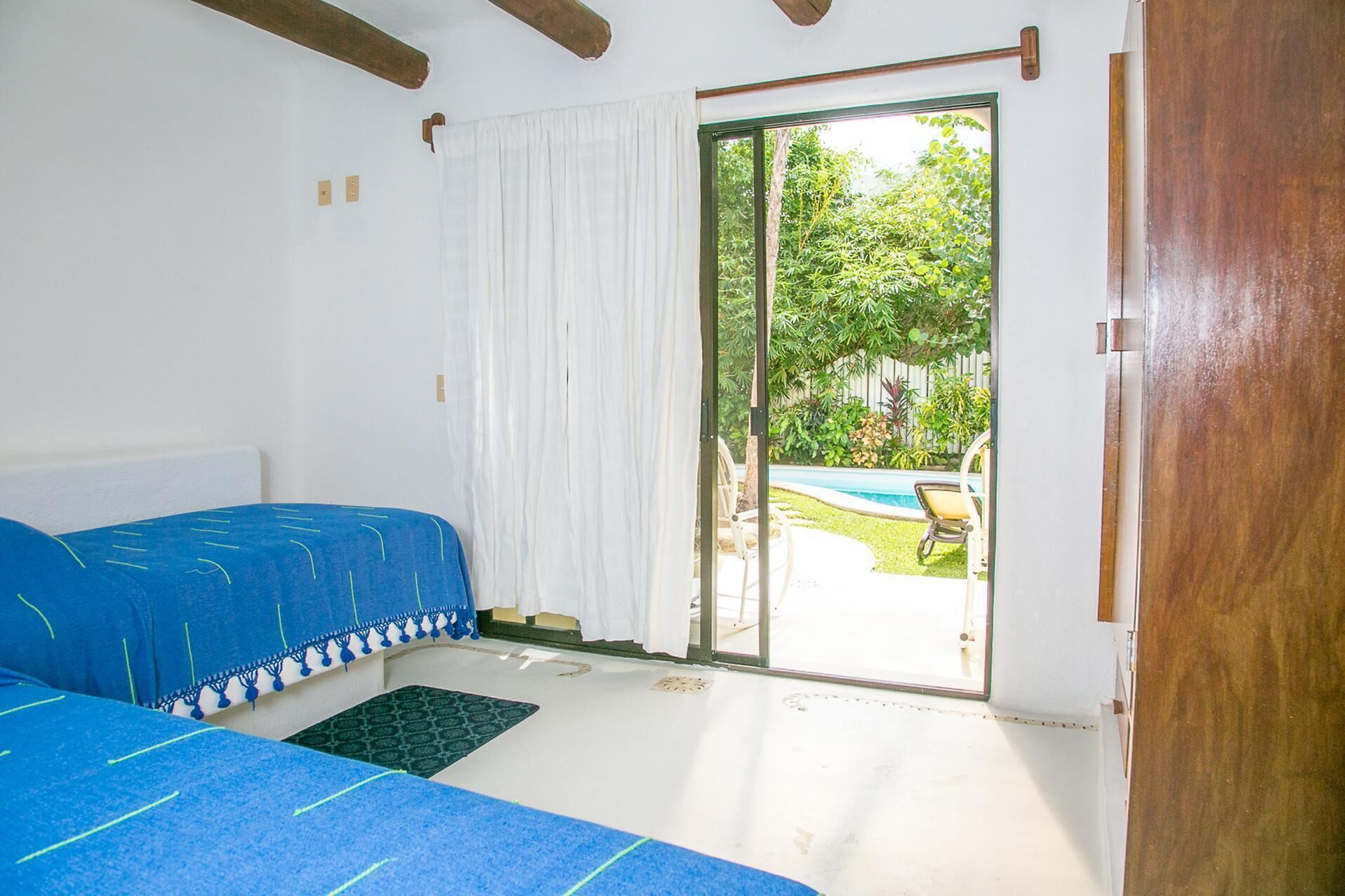 Un dormitorio con cama y puerta corrediza de vidrio que da a una zona de piscina.