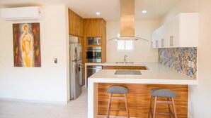 A modern kitchen with wooden cabinets, stainless steel appliances, and a tiled backsplash.