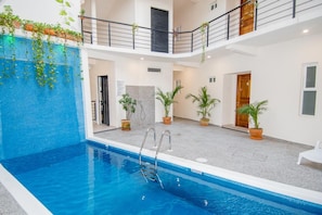 An indoor swimming pool with a clear view of the surrounding area, including a staircase, potted plants, and a door. - Villa Bonita PH (Santa María Huatulco)