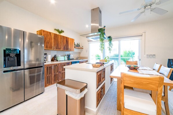 Una cocina moderna con electrodomésticos de acero inoxidable, armarios de madera y una isla central con asientos.