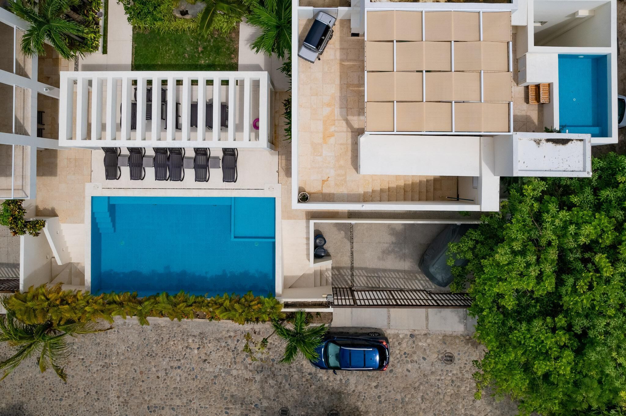 Vista aérea de un hotel moderno con piscina, mobiliario exterior y una zona de patio techada.