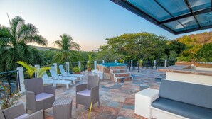 An outdoor patio with wicker furniture, a hot tub, and a view of the surrounding landscape.