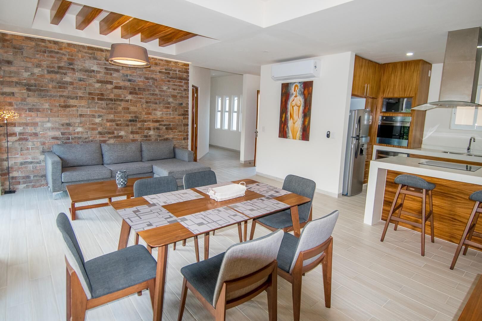 A modern living space with a dining area, a sofa, and a kitchen.