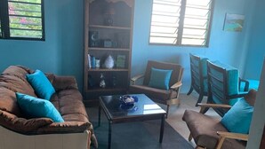 A living room with a brown sofa, a coffee table, and a bookshelf. - New listing!  Amazing sunrises and ocean views (St John)