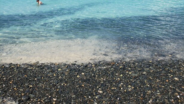 A beach with clear turquoise water, pebbly shore, and boats in the distance. - New listing!  Amazing sunrises and ocean views (St John)