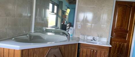 A bathroom with a large bathtub, wooden vanity, and a mirror.
