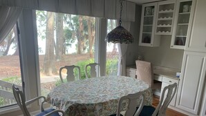 A dining area with a round table, white chairs, and a patterned tablecloth.