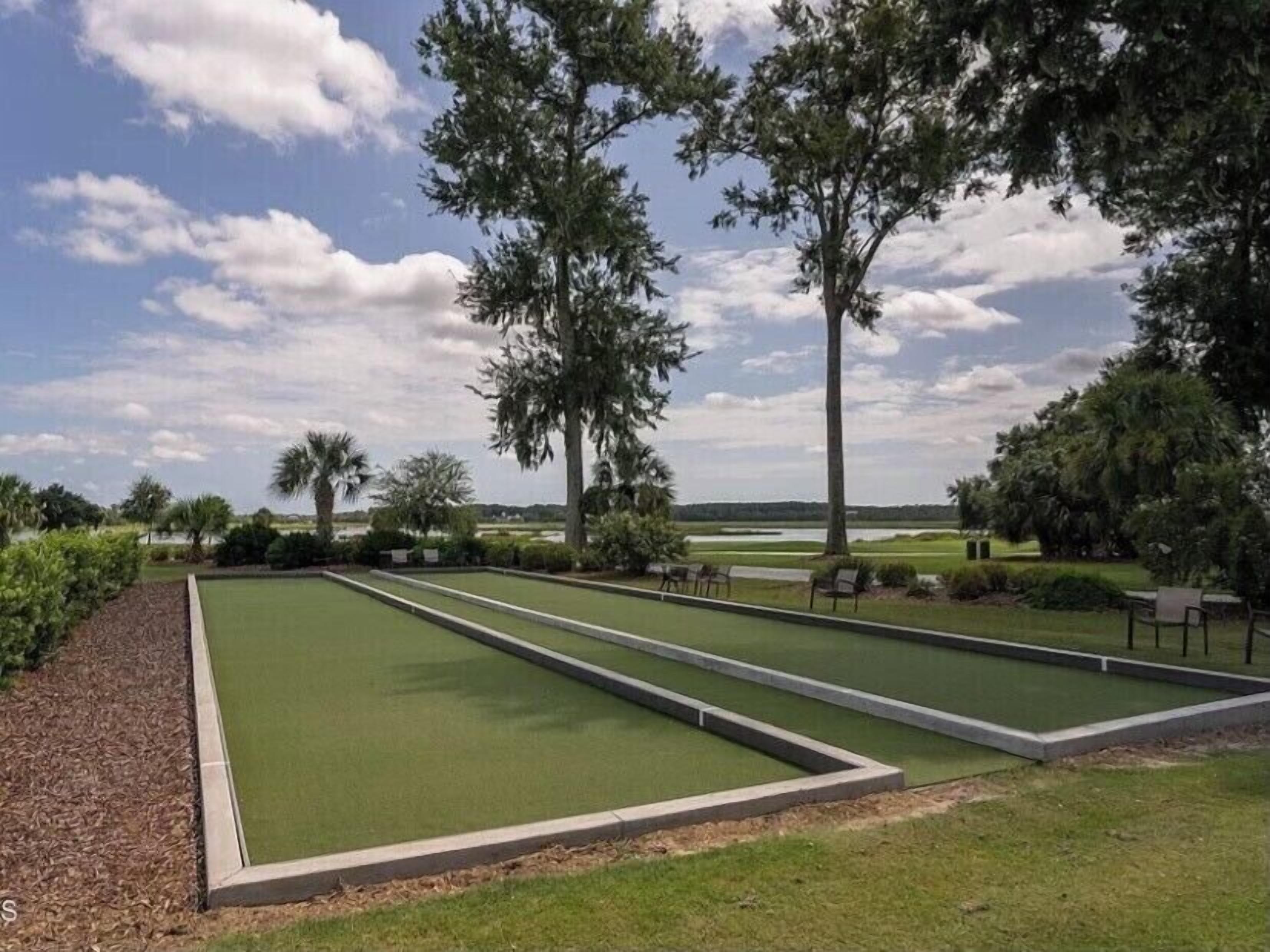 A croquet field with three lanes, surrounded by trees and a clear sky.