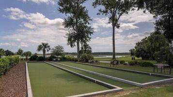 A croquet field with three lanes, surrounded by trees and a clear sky.